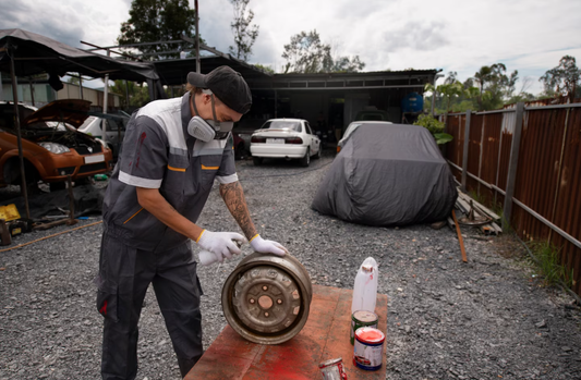 Worker handling old car parts during a garage junk removal process in an outdoor workspace