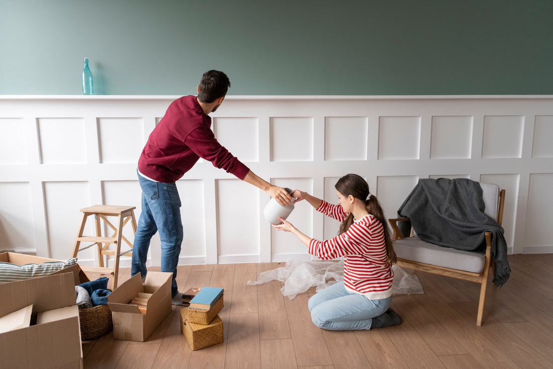 Two people are packing household items in a living room, preparing for junk removal in St. Petersburg, FL.